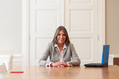 Portrait of smiling young woman sitting by table