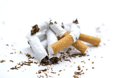 Close-up of crushed cigarettes over white background