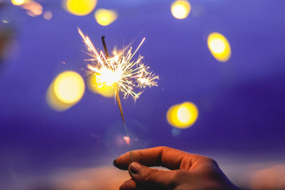 Person hand holding sparkler at night