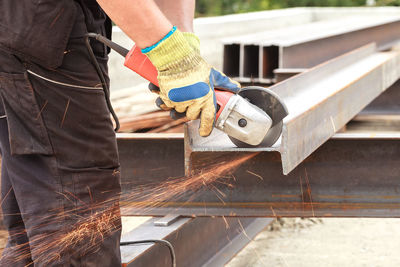 Midsection of man cutting metal