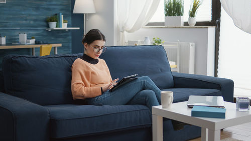 Young woman sitting on sofa at home