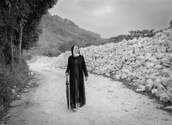 Rear view of woman standing on mountain against sky