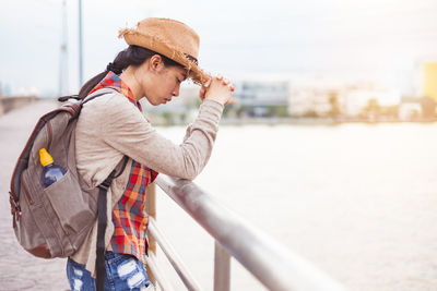 Man looking away while standing on railing in city