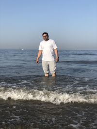 Full length of man standing on beach against clear sky