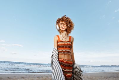 Side view of woman standing at beach against sky