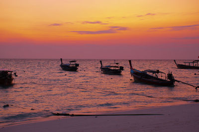 Boats in sea against sky during sunset