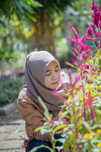 Asian muslim woman is holding flowers in garden
