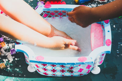 Cropped image of people washing hands in tub