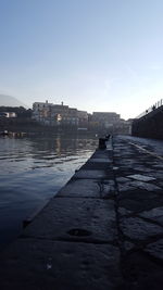 Bridge over river by buildings against sky