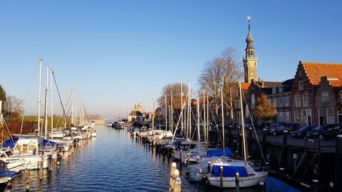 Boats moored at harbor against clear sky