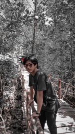 Side view of young man standing in forest