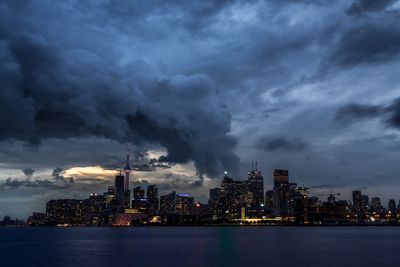 City at waterfront against cloudy sky