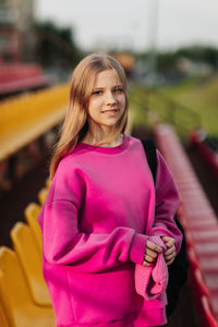 Portrait of a teenage student looking into the camera, against the background of the school stadium