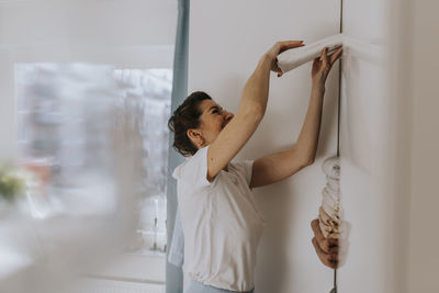 Smiling woman putting folded clothes in wardrobe