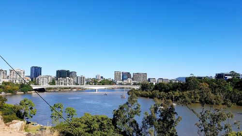 Scenic view of lake by buildings against clear blue sky