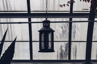 Close-up of lantern hanging against window