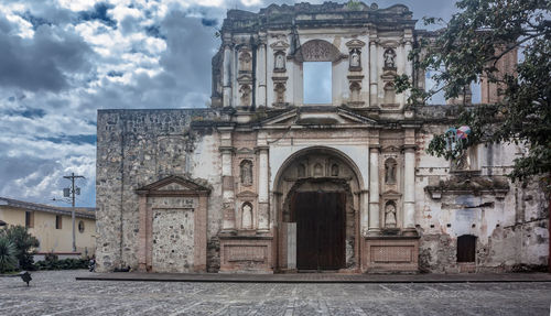 Facade of old building against cloudy sky