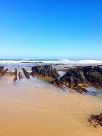 Scenic view of beach against clear blue sky