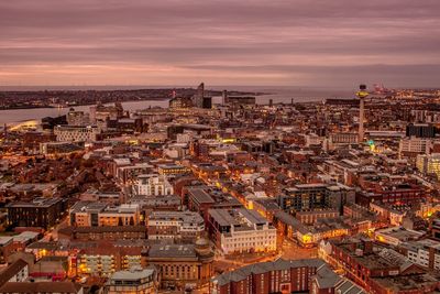 High angle view of buildings against cloudy sky in city during sunset