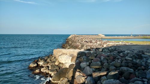 Rocks by sea against clear sky