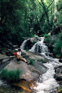 Man surfing in river stream amidst trees in forest