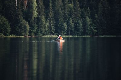 Man rowing boat in lake against trees