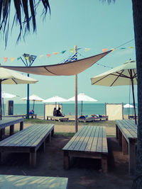 Chairs and table by swimming pool against clear blue sky