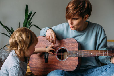 Little girl plays the guitar with her mother on the floor at home