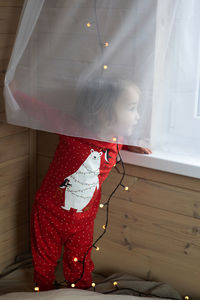 Close-up of girl standing by window at home