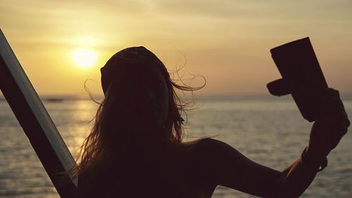 Silhouette woman on beach against sky during sunset