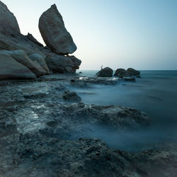 Scenic view of rocks in sea against clear sky