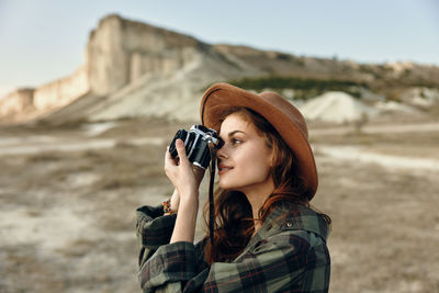 Side view of young woman photographing through camera