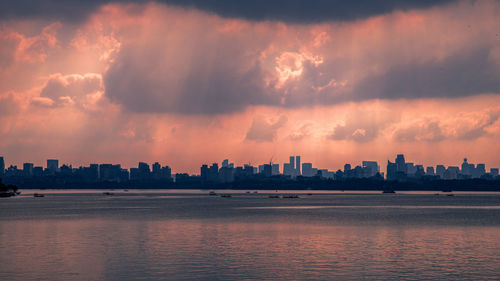 Panoramic view of sea and buildings against sky during sunset