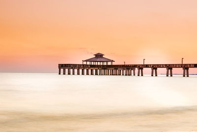 Pier over sea against sky during sunset