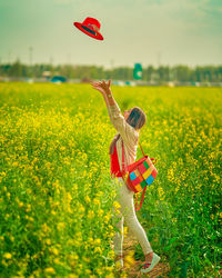 Woman standing on field by red flowers