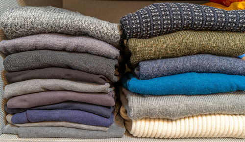 Stack of various types of woolen sweaters with autumn colors inside a wardrobe