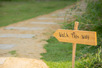 Walk this way sign writing on wooden label sign placing on the lawn in the garden 