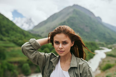 Young woman standing against mountain