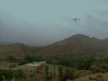 Airplane flying over mountain against sky