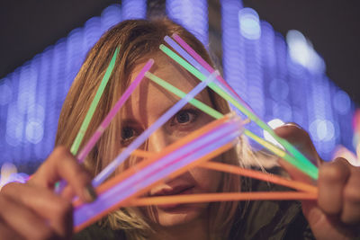 Close-up portrait of girl holding illuminated lighting equipment