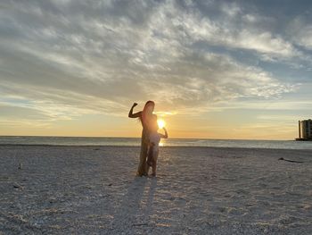 Man standing on beach against sky during sunset