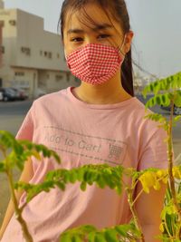 Portrait of girl wearing mask standing outdoors