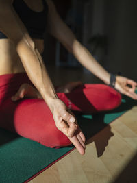 Yogini in sukhasana position on exercise mat at home in sunlight