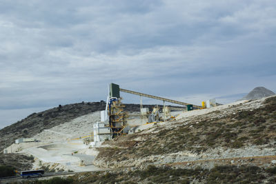 Low angle view of factory against cloudy sky