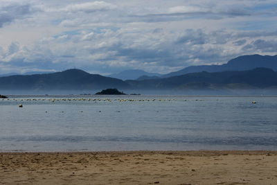 Scenic view of sea and mountains against sky