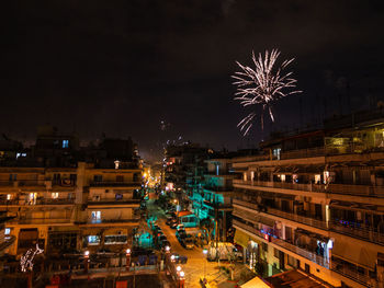 Firework display in city against sky at night