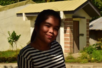 Portrait of smiling young woman standing outside house