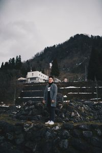 Man standing on rock against sky