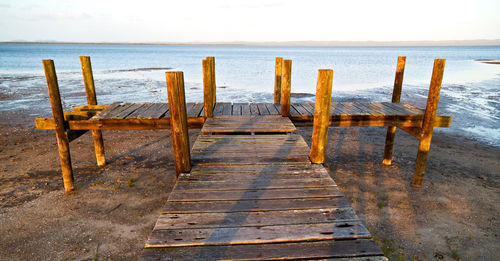 Wooden posts on beach against sky