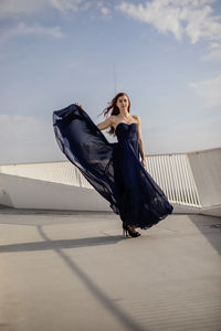 Portrait of young woman wearing blue dress while standing on building terrace